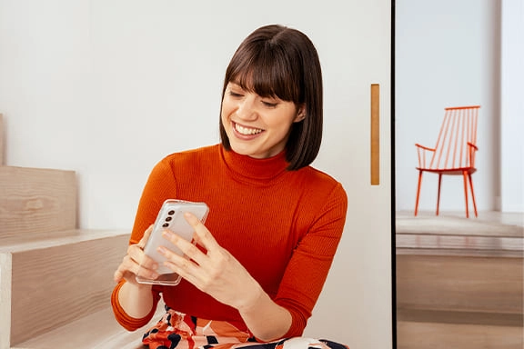Mulher com um telemóvel e capa de telemóvel da Samsung na mão.