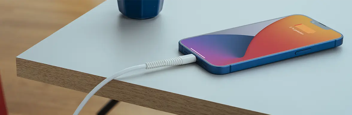 Um iPhone carrega lentamente enquanto está pousado na mesa.