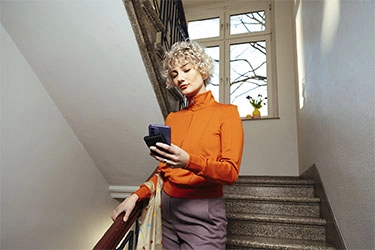 Mulher a descer escadas, o seu telemóvel é carregado através de um powerbank.