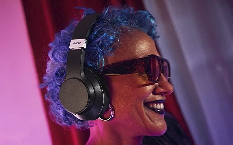 Uma mulher numa escada rolante usa auscultadores e olha para o seu smartphone.