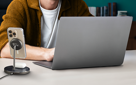 At a workstation, smartphones and headphones are charged via a wireless charging station.