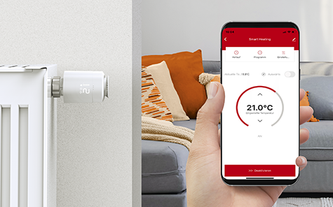 Hand holding a smartphone with the Hama app open to control the smart heating thermostat.
